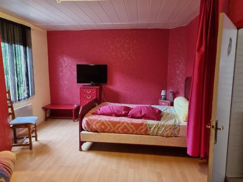a bedroom with a bed and a red wall at Petite maison in Vendat