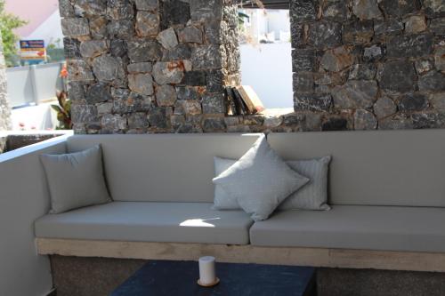 a couch with pillows sitting in front of a stone wall at Chill and Thrill Apartments in Mastichari