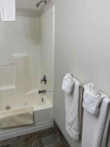 a white bathroom with a bath tub and towels at Colonial Motel in North Conway