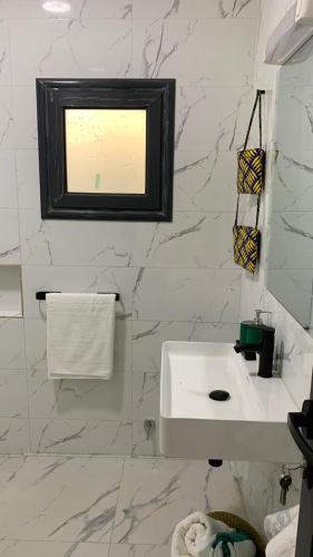 a white bathroom with a sink and a window at Mica Apartments in Sere Kunda