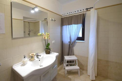 Baño blanco con lavabo y espejo en Antica Aia B&B, en Cisternino