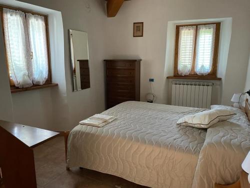 a bedroom with a bed and a dresser and windows at THE DORMOUSE - Il Ghiro in Reusa