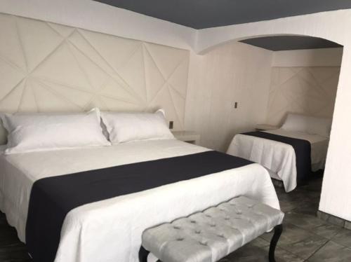 a bedroom with two beds and a bench in it at Hotel Nuevo Bernal in Bernal