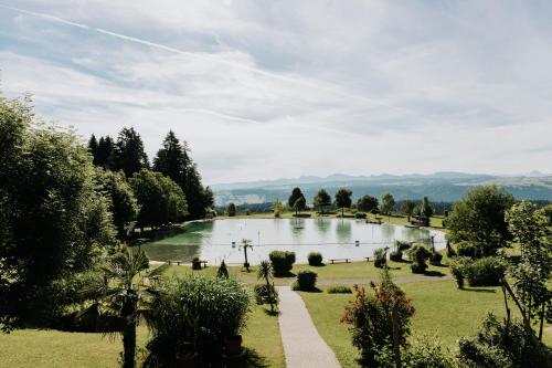 a view of a pond in a park with trees at HEIMATEL - Suiten, Apartments und Studios in Scheidegg