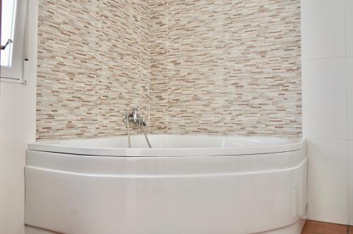 a white tub in a bathroom with a brick wall at ALAMANCHA in Casas de los Pinos