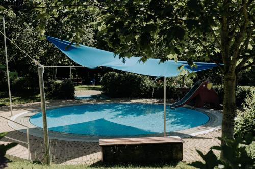 a blue umbrella over a swimming pool with a slide at HEIMATEL - Suiten, Apartments und Studios in Scheidegg