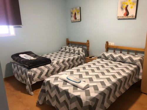ein Zimmer mit 2 Betten und einem Stuhl darin in der Unterkunft Hostal Casa Alonso in Atarfe