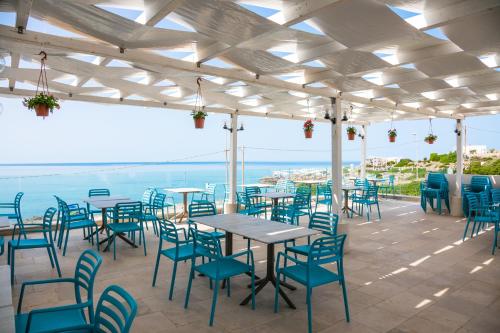 a patio with tables and chairs and the ocean at Hotel Magna Grecia in Leuca