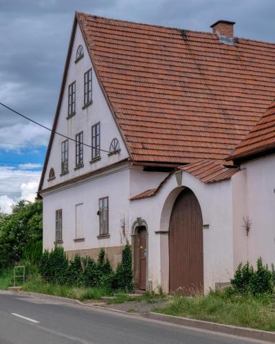 an old white house with a brown roof at Apartmány v broumovském statku in Broumov