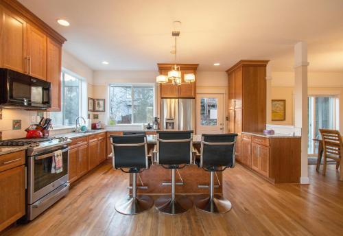 a kitchen with wooden cabinets and a island with bar stools at Hazel House home in Hood River