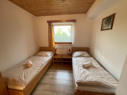 2 Betten in einem kleinen Zimmer mit Fenster in der Unterkunft Chata Relax in Námestovo