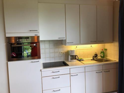 a kitchen with white cabinets and a sink and a refrigerator at Enjoy Durbuy 4 in Durbuy