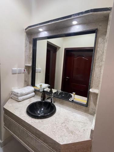 La salle de bains est pourvue d'un lavabo et d'un grand miroir. dans l'établissement الاتحاد الذهبية للشقق المخدومة 1, à Al Hofuf