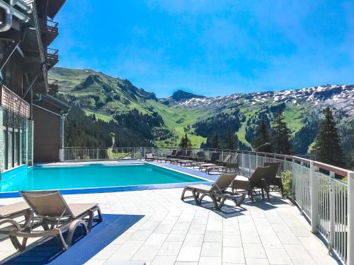 d'un balcon avec une piscine, des chaises et des montagnes. dans l'établissement Spacious Family 2-bed, 2-bath with parking, private piste, à Flaine