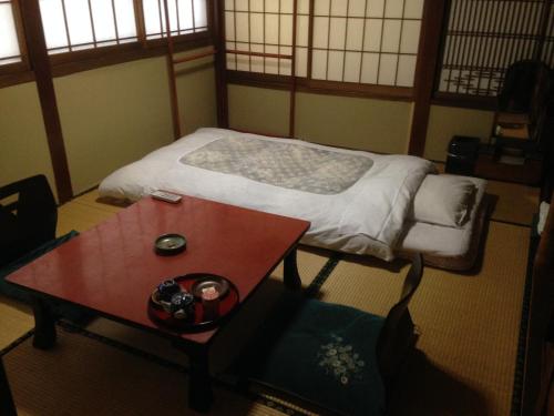 長野市にある中央館　清水屋旅館のベッドとテーブル付きの小さな部屋