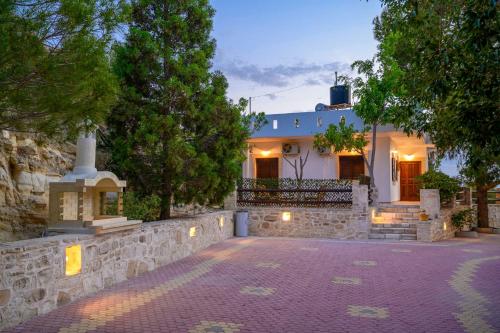 a house with a stone wall and a driveway at Villas Alexandros in Kalamaki