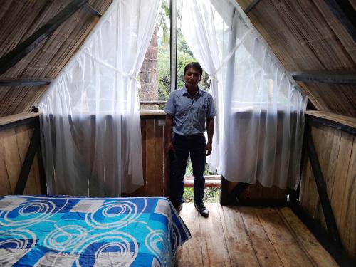 a man standing in the doorway of a house with a bed at Posada Fin del Mundo in Mocoa