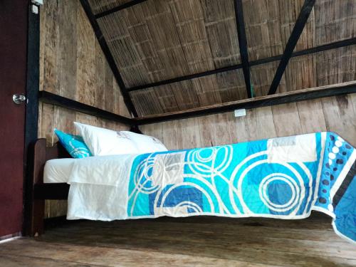 a bed in a room with a wooden wall at Posada Fin del Mundo in Mocoa