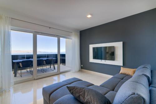 a living room with a blue couch and a dining room at APARTMANI OLIMP in Sveti Juraj