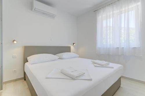 a white bedroom with a bed with two towels on it at APARTMANI OLIMP in Sveti Juraj