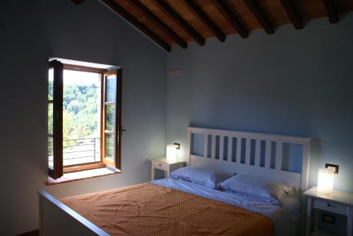a bedroom with a bed and a window and two lamps at Tramonto Casa Barga Toscana ristrutturata 2021 in Barga