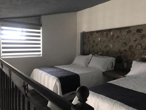 a hotel room with two beds and a window at Hotel Nuevo Bernal in Bernal