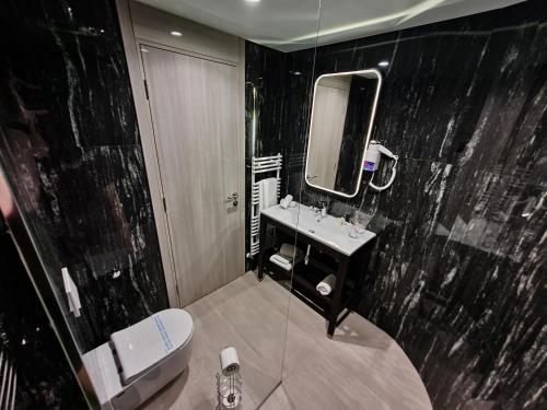 a bathroom with a toilet and a sink and a mirror at Hotel City Code in Zenica