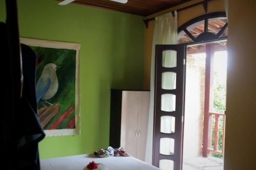 um quarto com uma pintura de pássaro na parede e uma janela em Pousada Ilha De Boipeba na Ilha de Boipeba