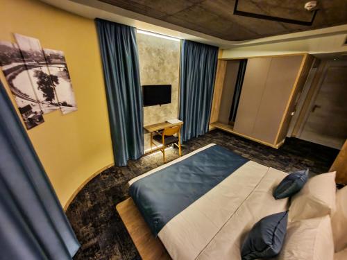 a bedroom with a bed and a desk and a television at Hotel City Code in Zenica