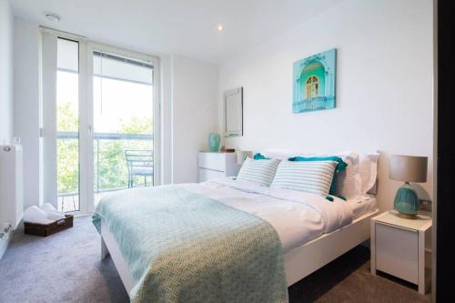 a white bedroom with a large bed and a window at Wild Roses Serviced Apartments - Greenwich in London