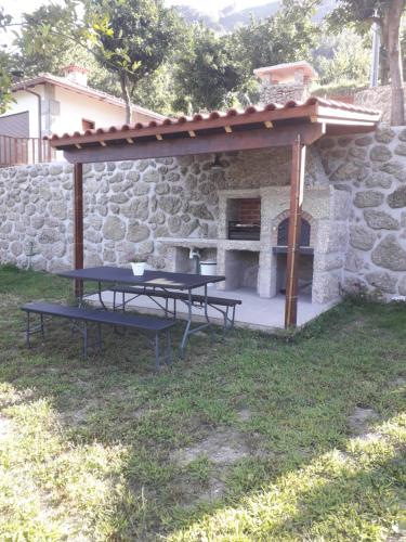 a picnic table with a stone oven in a yard at Quinta da Casa Matilde - NATURE HOUSE in Geres