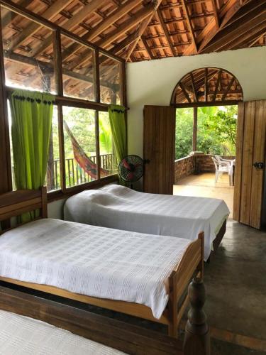 two beds in a room with windows and a patio at La Toscana Campestre in Viotá