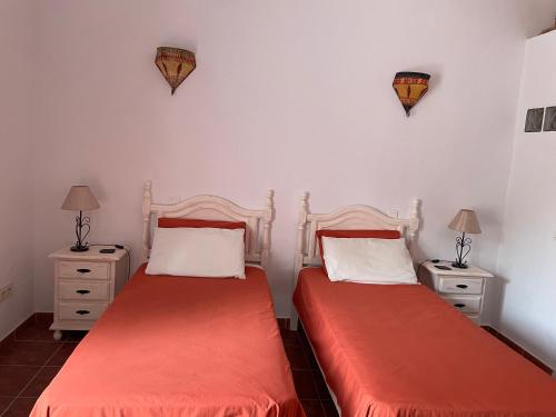 ComaresにあるViva Españaのベッド2台、ナイトスタンド、ランプが備わる客室です。
