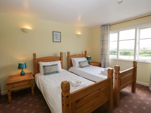 two twin beds in a room with a window at Wheelbarrow Cottage in Stoke Prior