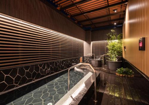 APA Hotel Ueno Ekimae في طوكيو: حمام مع حوض استحمام مع النباتات في دلاء