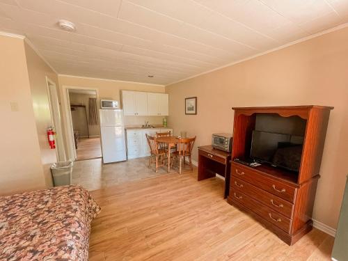 a living room with a television and a kitchen at Silverwood Motel in Cavendish