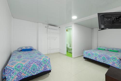 a bedroom with two beds and a tv on the wall at La isla inn in San Andrés