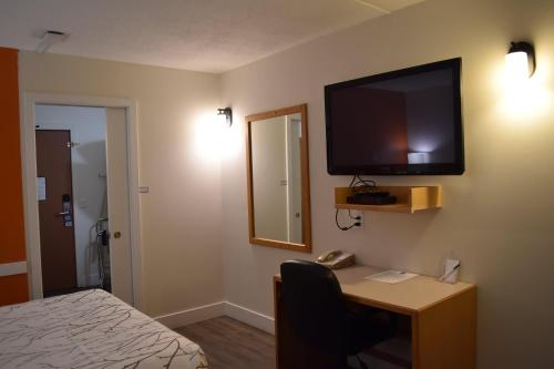 a hotel room with a desk and a television on the wall at Canadas Best Value Inn & Suites-Castlegar in Castlegar