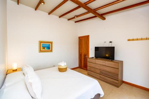 a bedroom with a bed and a flat screen tv at Hotel Punta Camarón Bungalows & Suites in Zorritos