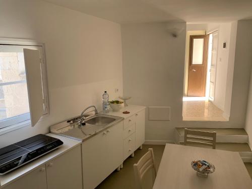 d'une cuisine avec un évier, une table et une fenêtre. dans l'établissement Palazzo Moschettini, à Martano