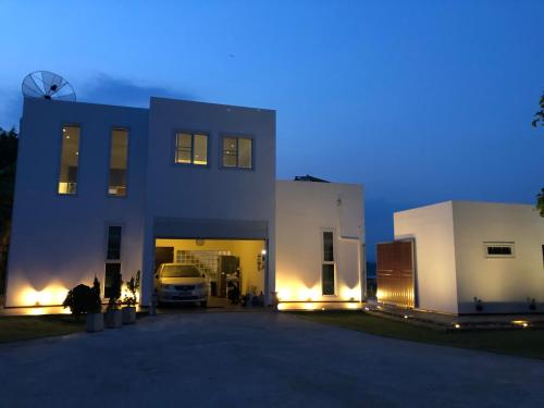 a white house with a car parked in the driveway at Chiang Khan Riverside Pool Villa in Chiang Khan