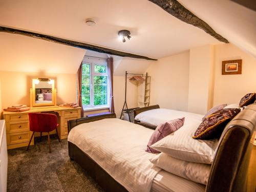 a bedroom with two beds and a desk and a mirror at Eleri Cottage in Great Malvern