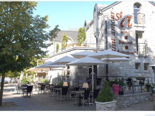 a restaurant with tables and umbrellas in front of a building at Enjoy Durbuy 4 in Durbuy