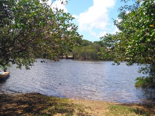 um lago com árvores e um barco na água em Casa 2/4 em Itacimirim - Beira do Rio Pojuca em Camaçari