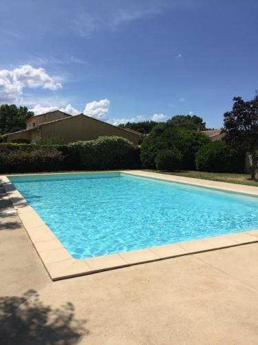 une grande piscine bleue devant une maison dans l'établissement Appartement Résidence Privé avec PARKING WIFI CLIM PISCINE, à Avignon