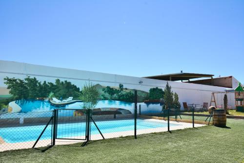 a swimming pool with a painting on the side of a building at ALAMANCHA in Casas de los Pinos