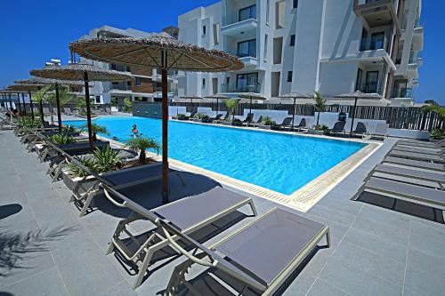 a swimming pool with lounge chairs and umbrellas at Golden Tree Apartment in Paralimni