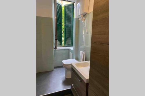 a bathroom with a toilet and a sink and a window at Piazza Anco Marzio fronte mare casa con giardino in Lido di Ostia