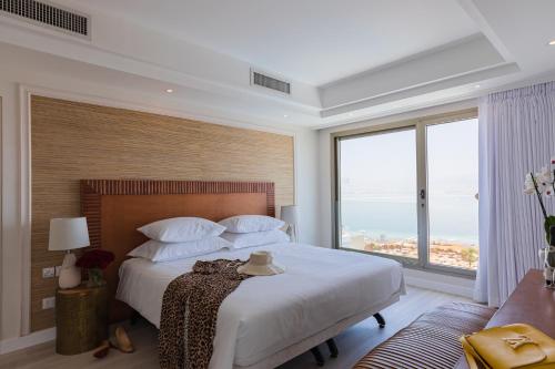 a bedroom with a large bed with a large window at Enjoy Dead Sea Hotel -Formerly Daniel in Ein Bokek