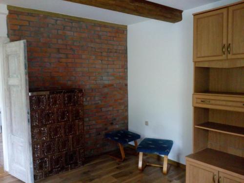 una camera con un muro di mattoni e due sedie accanto a uno scaffale di Stare Sioło a Wysokie